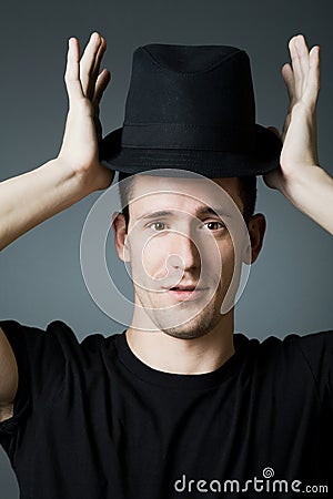 Handsome man in black shirt holding black hat.