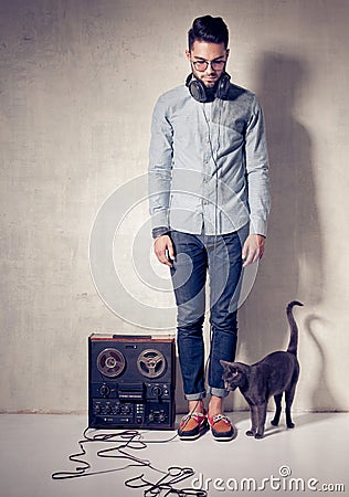 Handsome man and cat listening to music on a magnetophone