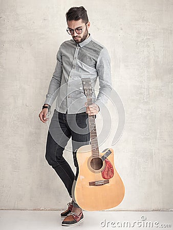 Handsome man holding an acoustic guitar against grunge wall