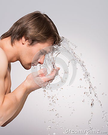 Handsome man washing his clean face.