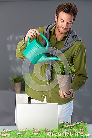 Handsome man watering plant at home