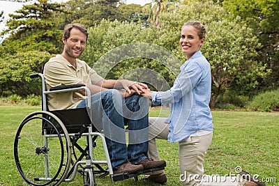 Handsome man in wheelchair with partner kneeling beside him