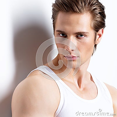 Handsome man in white shirt poses at studio.