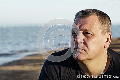 Handsome middle-aged man thinking at the beach