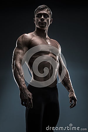 Handsome muscular bodybuilder posing over black background