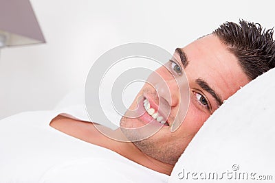 Handsome sensual man smiling lying in bed