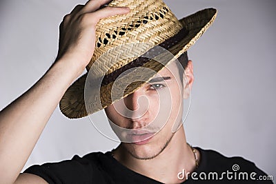 Handsome sultry sexy young man with straw hat