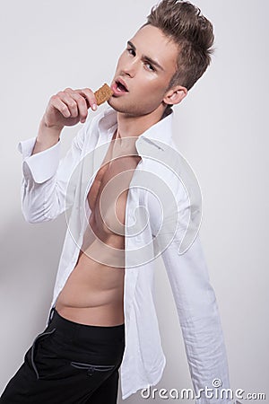 Handsome young male in white shirt with cookie