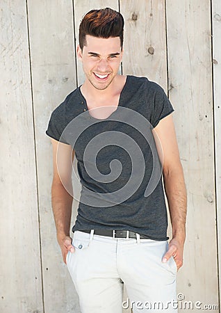 Handsome young man laughing with hands in pocket