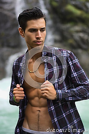 Handsome young man near mountain waterfall with op