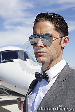 Handsome young men wearing sunglasses with private plane in background
