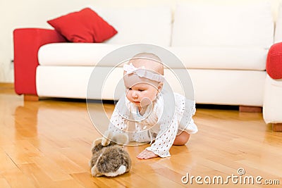 Happy baby girl crawling to rabbit toy