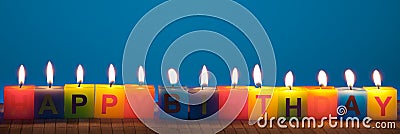 Happy birthday lit candles on blue