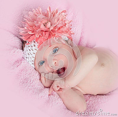 Happy blue eyed baby girl with a headband and flower