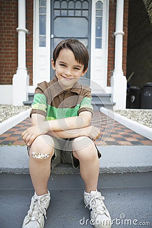 Happy Boy Sitting On Front Steps Of House