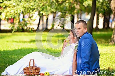 Happy bride and groom on their wedding sits on the grass in park