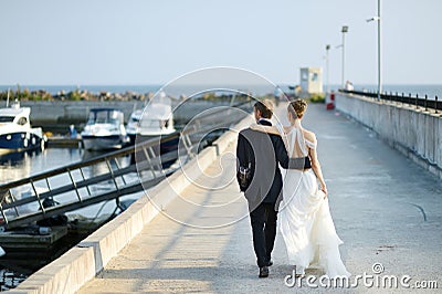 Happy bride and groom walking on pier