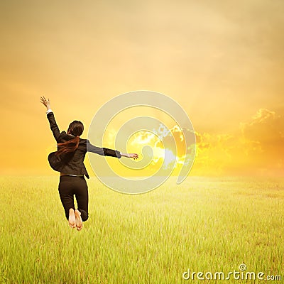 Happy business woman jumping in green rice field and sunset