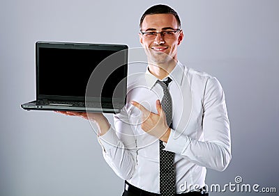 Happy businessman standing with laptop