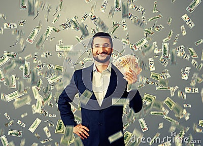 Happy businessman standing under money rain