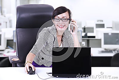 Happy businesswoman chatting on phone at office