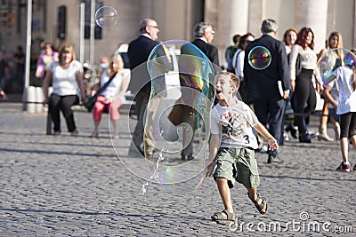 Happy child running towards a soap bubble