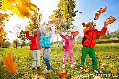 Happy children playing with flying leaves in park