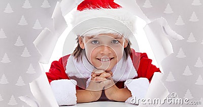 Happy christmas boy smiling through hole in wrapping paper