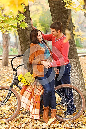 Happy couple with bicycle walking in autumn park