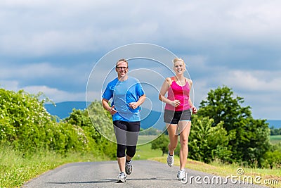 Happy couple doing sport jogging on rural street