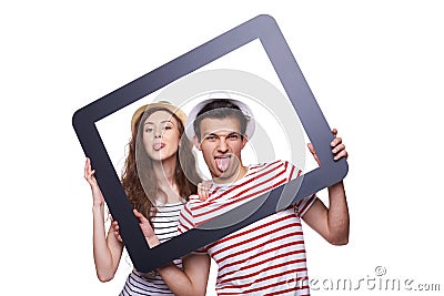 Happy couple showing tongue through tablet frame