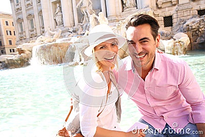 Happy couple sitting near Trevi fountain in Rome