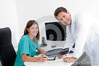 Happy Dentist And Assistant With X-Ray Report