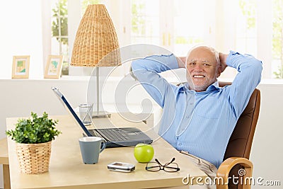 Happy elderly man smiling at desk