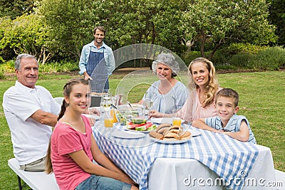Happy extended family having a barbecue being cooked by father