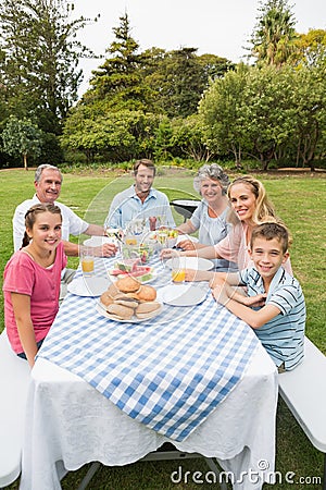 Happy extended family having dinner outdoors at picnic table