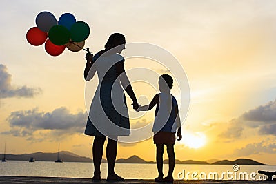 Happy family with balloons at sunset