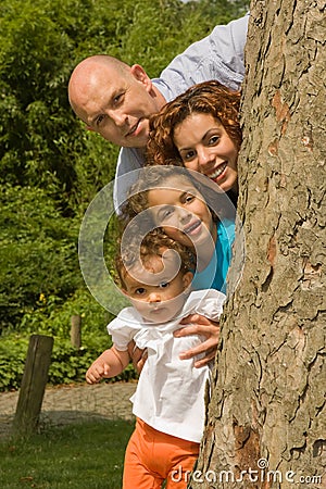 Happy family behind a tree