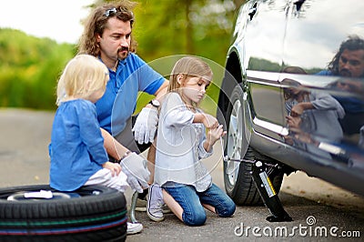 Happy family changing a car wheel