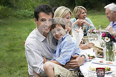 Happy Family Dining At Table In Garden