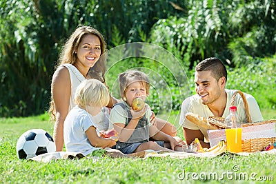 Happy family of four having picnic