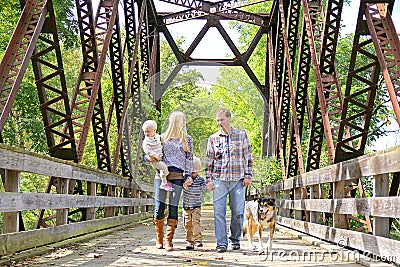 Happy Family of Four People Walking Dog Outside on Bridge