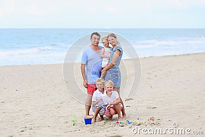 Happy family of 5 having fun on the beach