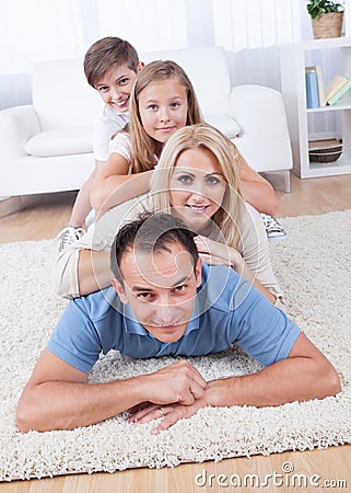 Happy Family Lying Heaped On Carpet In Living Room