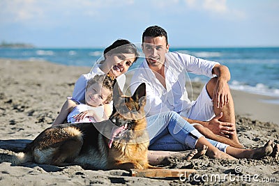 Happy family playing with dog on beach