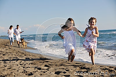 Happy family playing with dog on beach