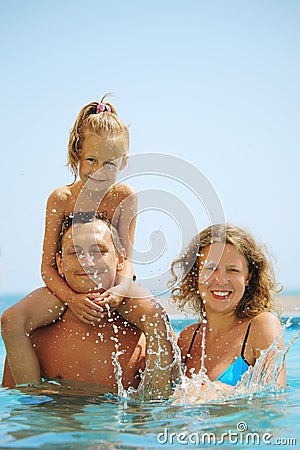 Happy family in pool. Splashing water.