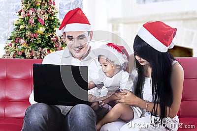 Happy family in santa hat using a laptop