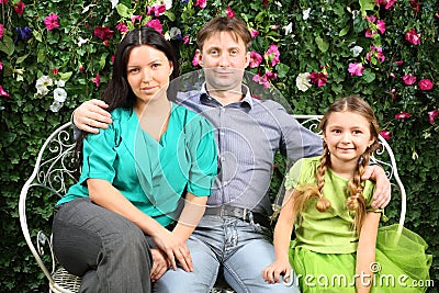 Happy family sit on white bench in garden