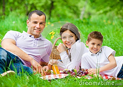 Happy family of three has picnic in park